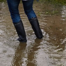 Persons legs with rain boots on in standing water to ankles